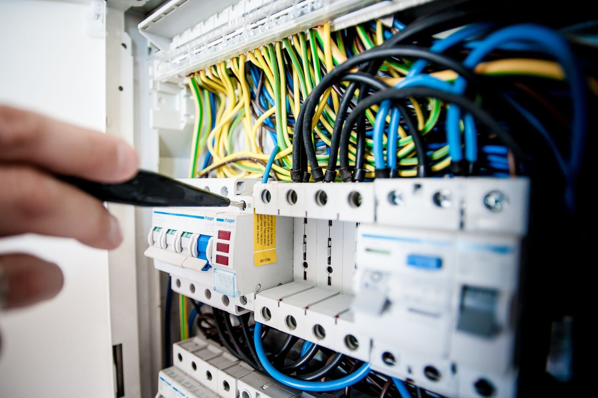 Mano de un electricista trabajando en las protecciones de un cuadro con el cableado a la vista