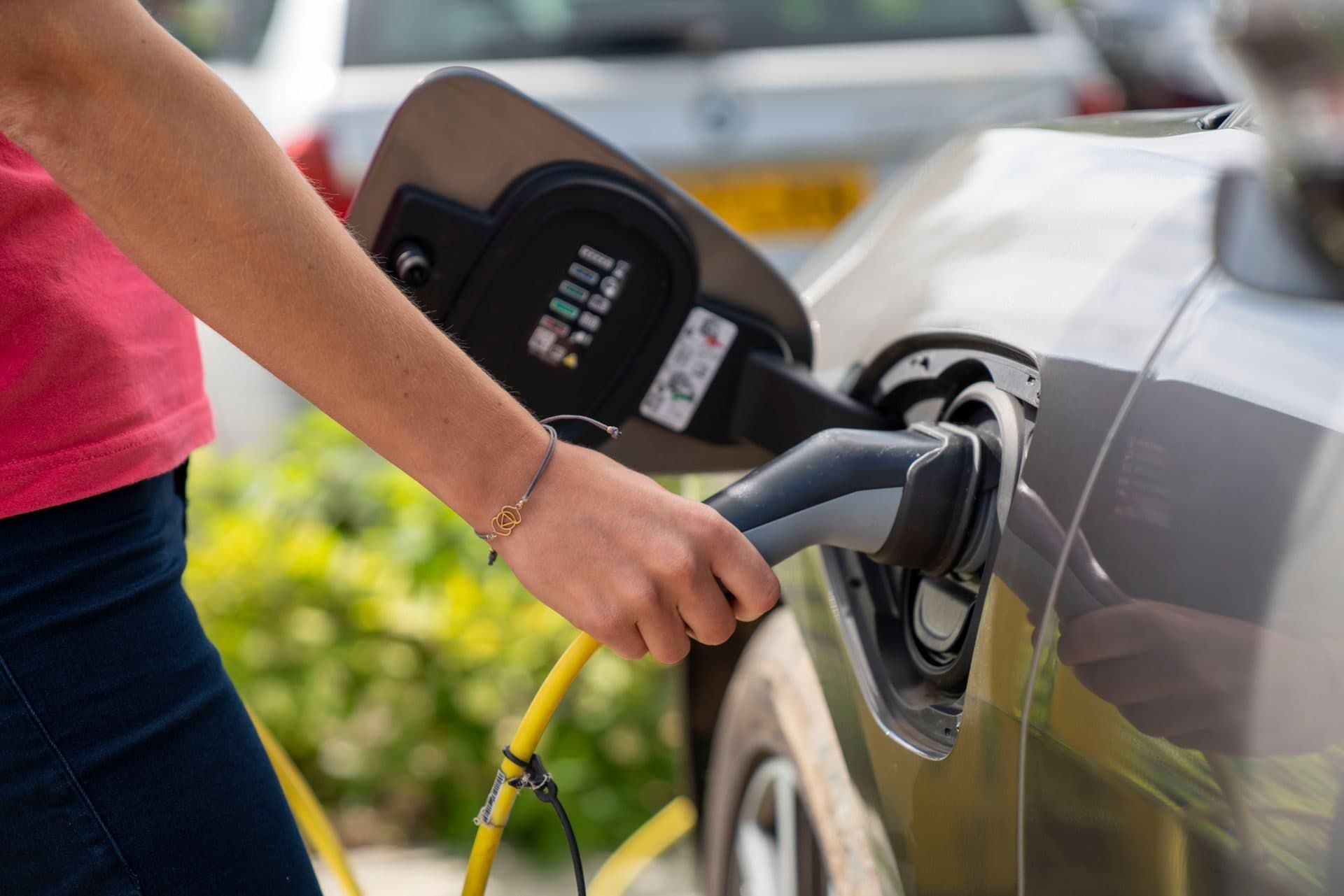 Mano enchufando el conector de carga en el puerto de un coche eléctrico