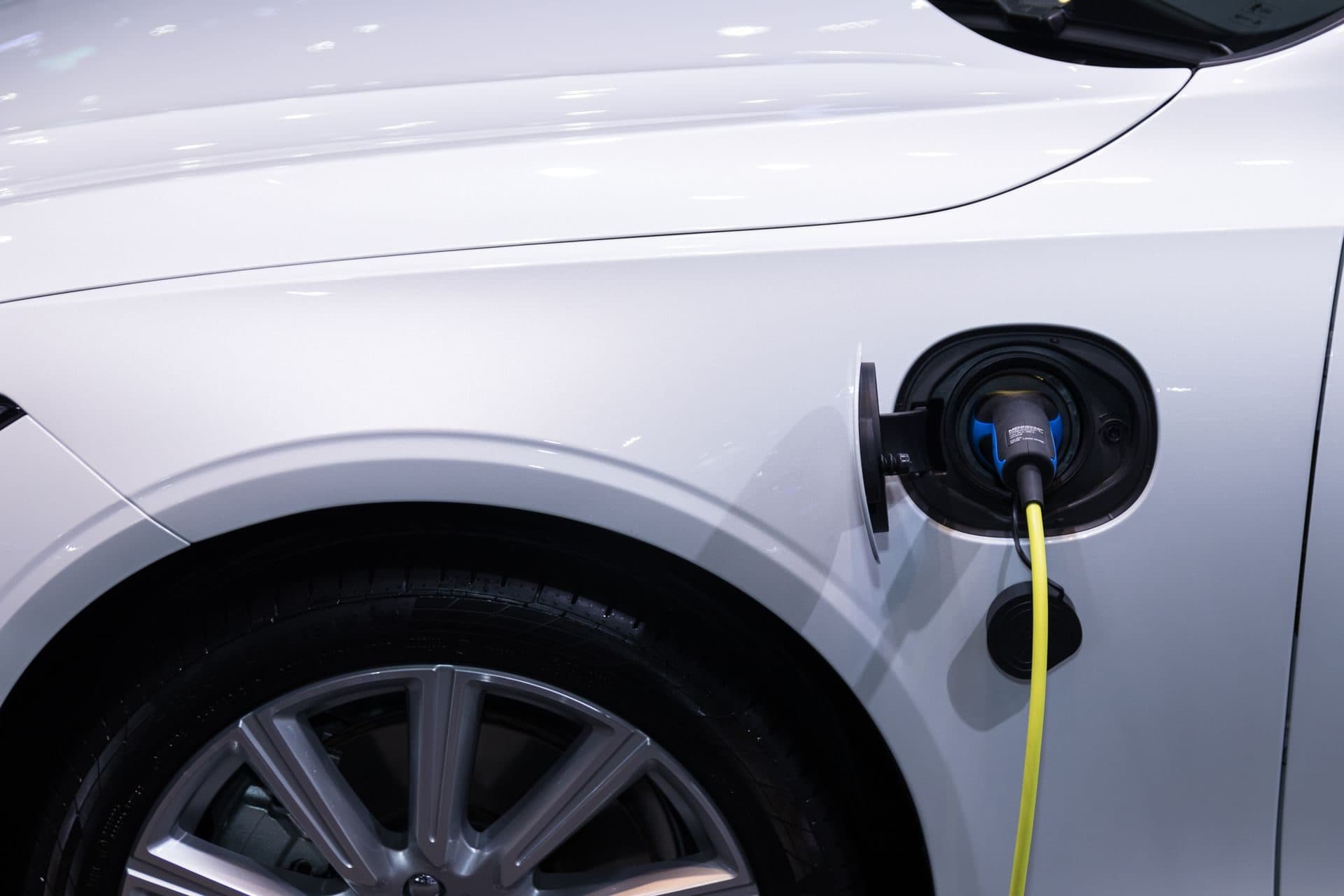 Coche eléctrico blanco con el cable de carga conectado a su puerto
